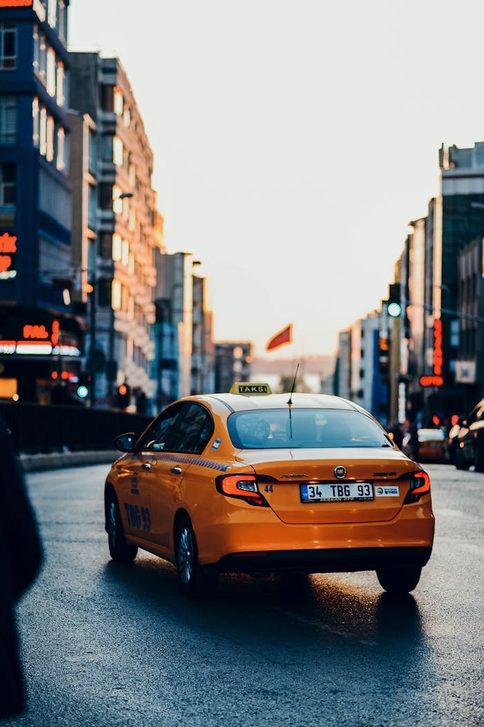 Vibrant yellow taxi cruising through a busy city street during sunset, capturing the essence of urban life.