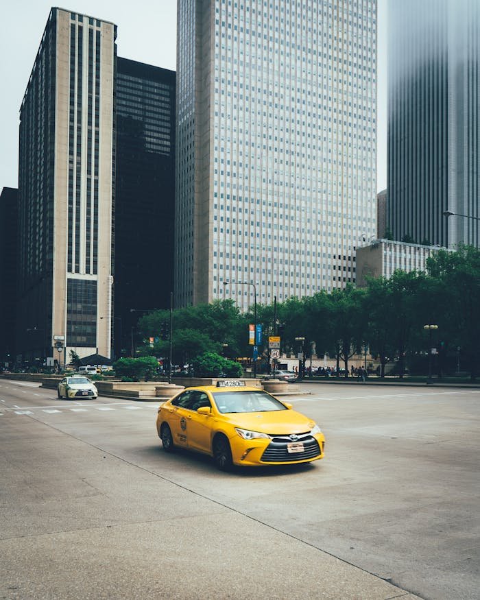 A yellow taxi drives through the bustling streets of downtown Chicago, surrounded by skyscrapers.