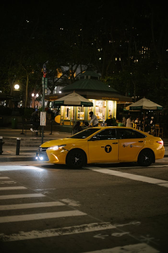 Services A yellow taxi drives through a dimly lit urban street at night with blurred city lights.